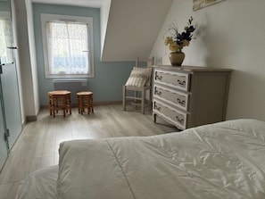 A bedroom with a bed, a dresser, two chairs, a window with curtains, and a radiator. - House 4 persons in Saint Gildas de Rhuys, near the Ocean (Saint-Gildas-de-Rhuys)