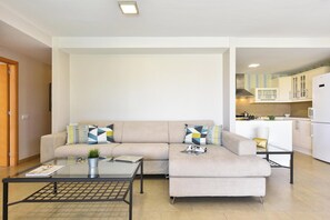 Ein Wohnzimmer mit einer Couch, einem Couchtisch und einer Küche im Hintergrund.