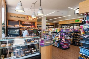 A bakery section with a display case of baked goods, a refrigerated display, and shelves stocked with packaged snacks and beverages.