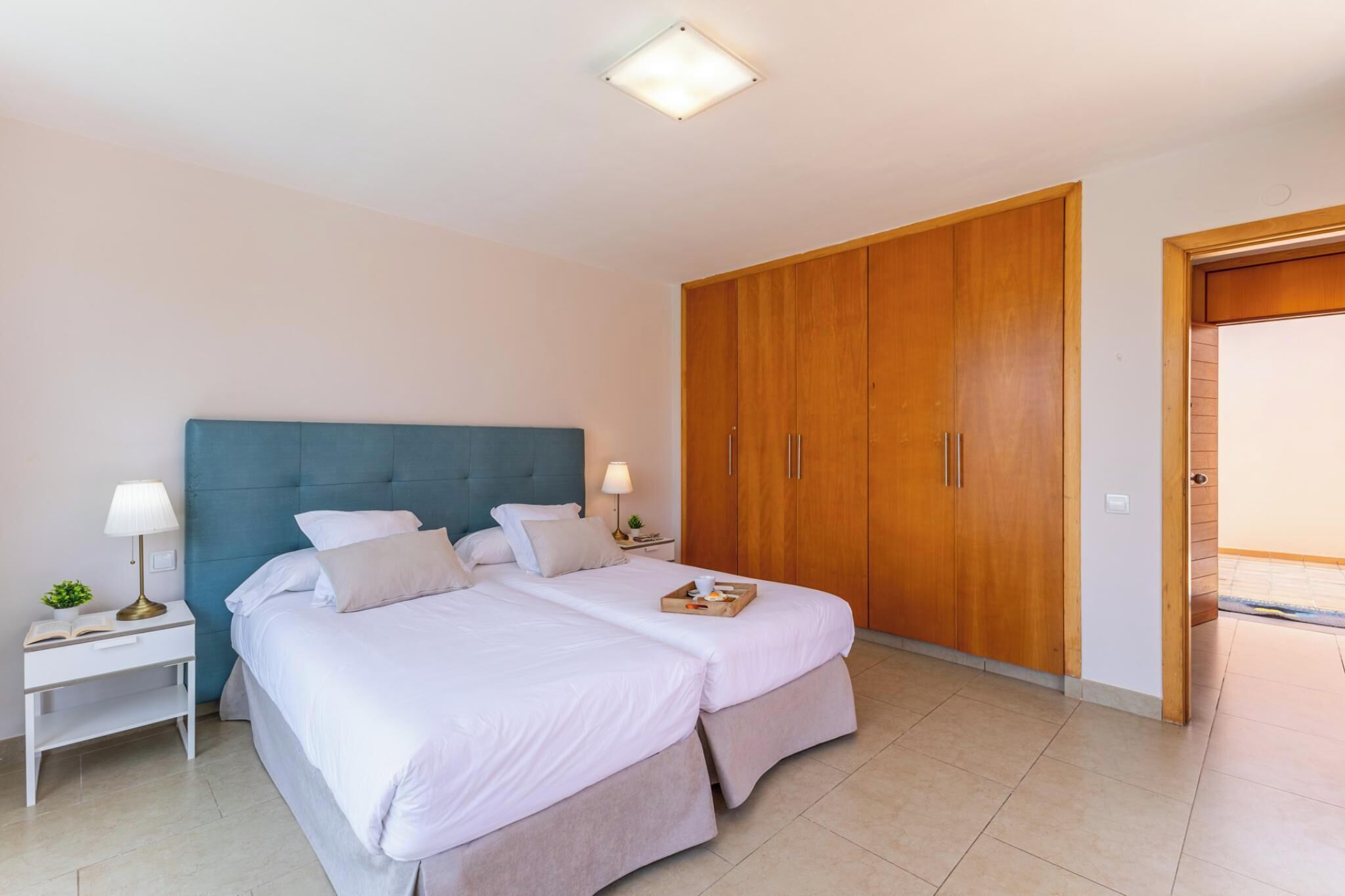 Un lit double avec une tête de lit, des tables de chevet avec des lampes et une armoire.