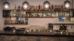 A bar area with shelves of liquor bottles, glasses, and coffee machines. - SOMA Dream Hotel  (Georgetown)