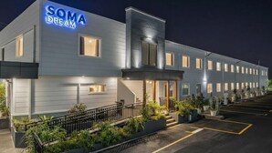 A modern hotel with a 'SOMA DREAM' sign, a covered entrance, and a parking lot. - SOMA Dream Hotel  (Georgetown)