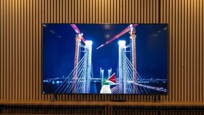 A television mounted on a wooden wall with a view of a bridge at night. - SOMA Dream Hotel  (Georgetown)