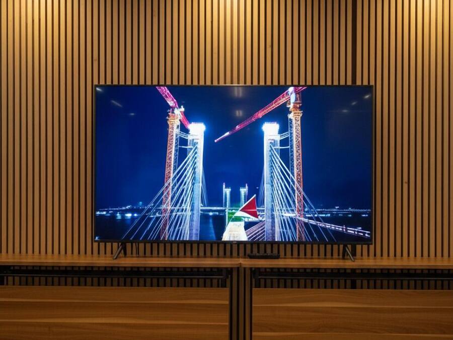 Un televisor montado en una pared de madera con vista a un puente de noche.