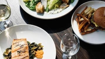 A table with various dishes including a salad, grilled salmon, a burger, and fries.