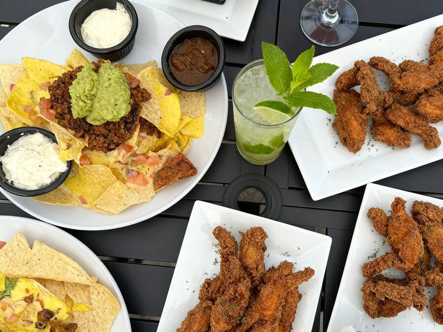 Un tavolo con nachos, pollo fritto, patatine fritte e un margarita.