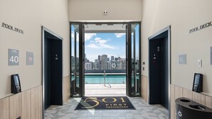 An entrance to a residential building with a pool view, numbered doors, and a trash bin.