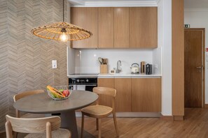 A modern kitchen with wooden cabinets, a dining table with chairs, a fruit bowl, and a hanging light fixture. - Two Towers - One-bedroom flat with balcony (Funchal)