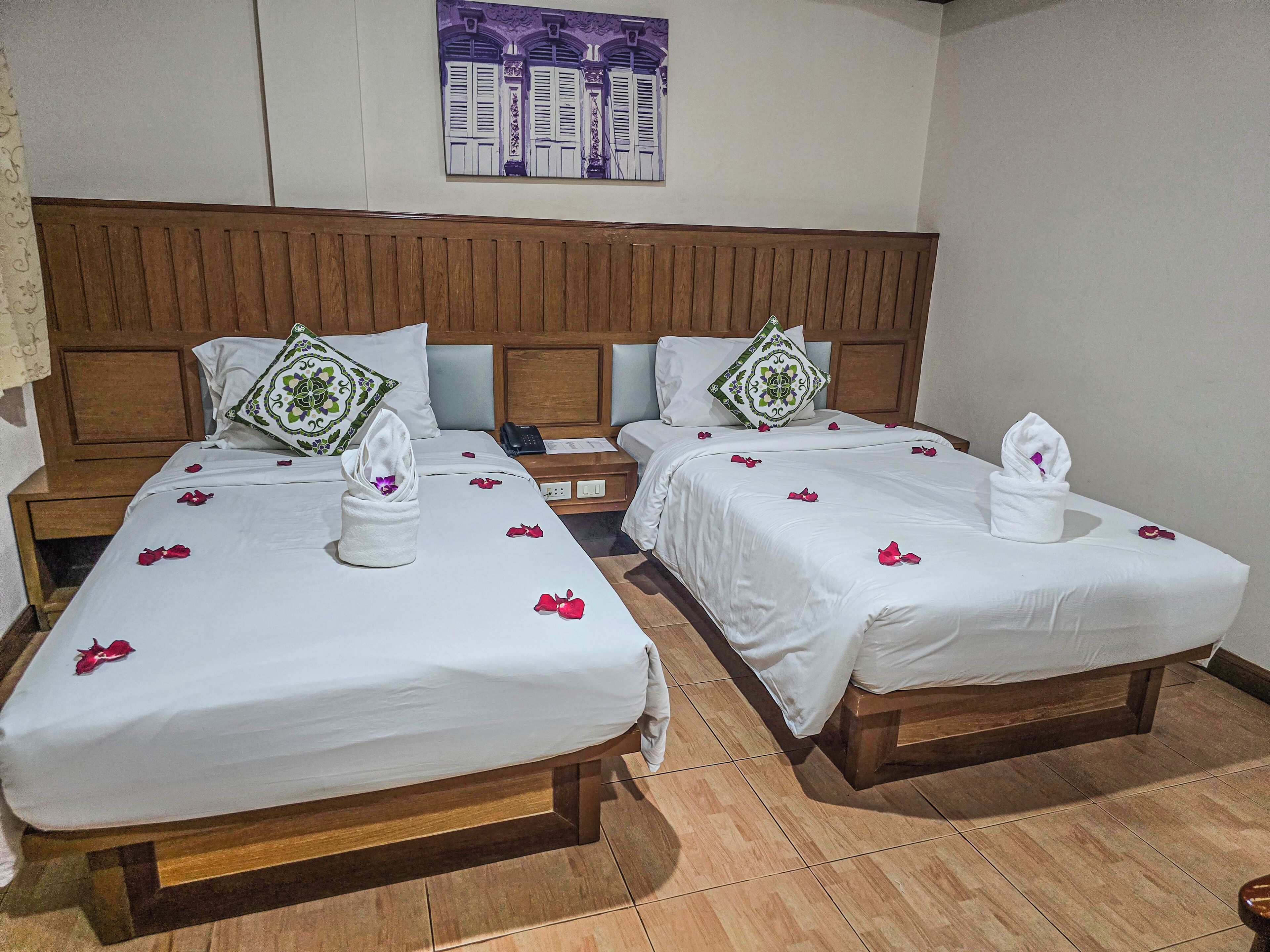 Habitación de hotel con dos camas, cabeceros de madera, ropa de cama blanca y una obra de arte colgada en la pared.