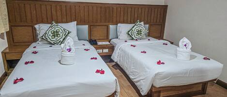 Habitación de hotel con dos camas, cabeceros de madera, ropa de cama blanca y una obra de arte colgada en la pared.