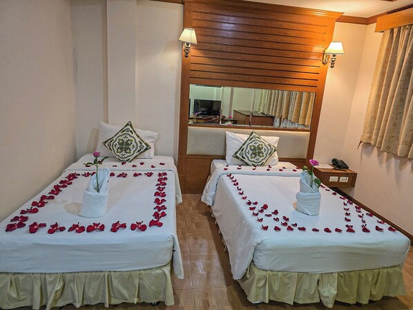 Two beds with rose petals, a mirror, and a telephone on a bedside table. - Saba Suites Hotel Patong Phuket (Patong)