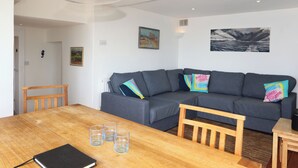 A living room with a grey sofa, wooden table, and glassware. - Blue Horizons seaside flat in town centre (Lyme Regis)