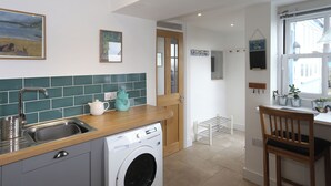 A kitchen with a washing machine, a sink, and a wooden countertop. - Blue Horizons seaside flat in town centre (Lyme Regis)