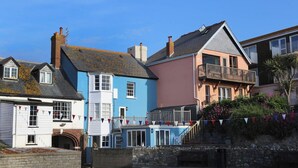 A row of colorful buildings with a stone wall and a flag. - Blue Horizons seaside flat in town centre (Lyme Regis)