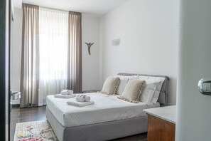Une chambre à coucher avec un lit, des rideaux, un élément de décoration murale et une table de chevet.