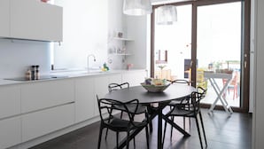 Eine moderne Küche mit weißen Schränken, einem Esstisch mit Stühlen und einem großen Fenster.