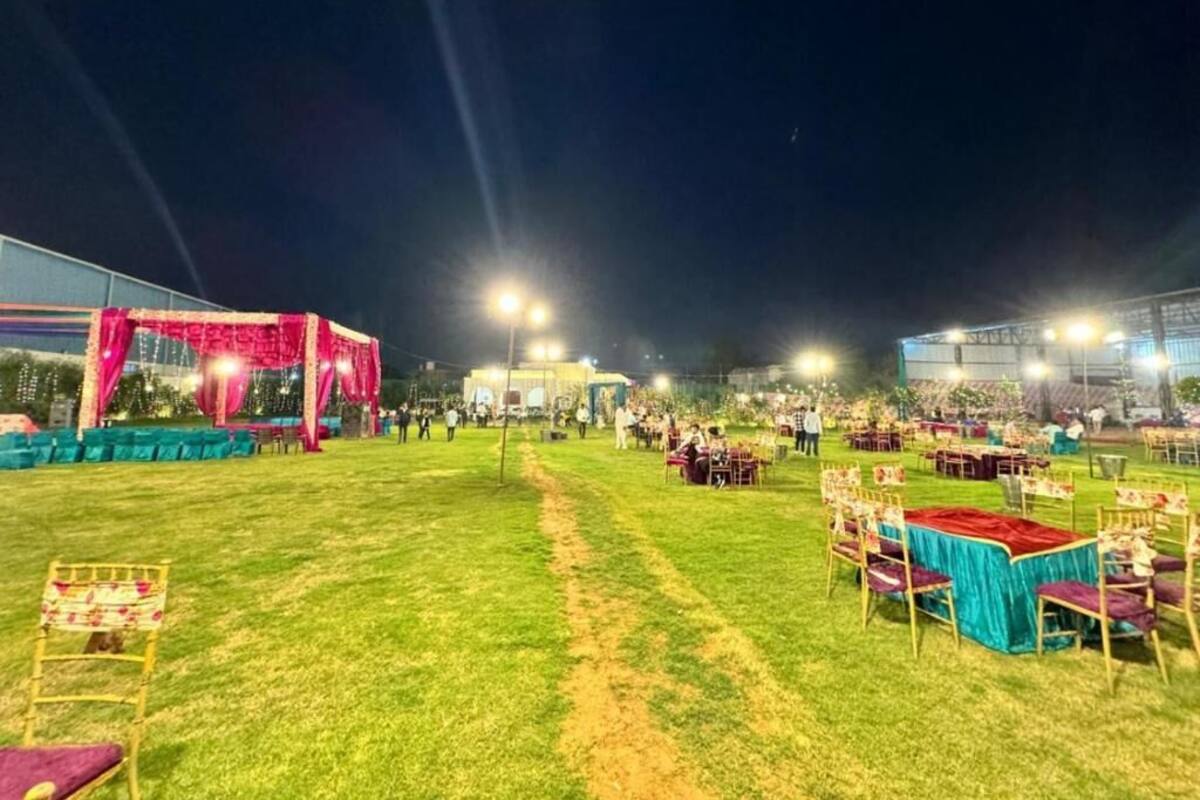An outdoor event space with tables and chairs, a stage, and lighting.
