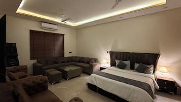 A modern bedroom with a bed, a sofa, a coffee table, and a ceiling fan.