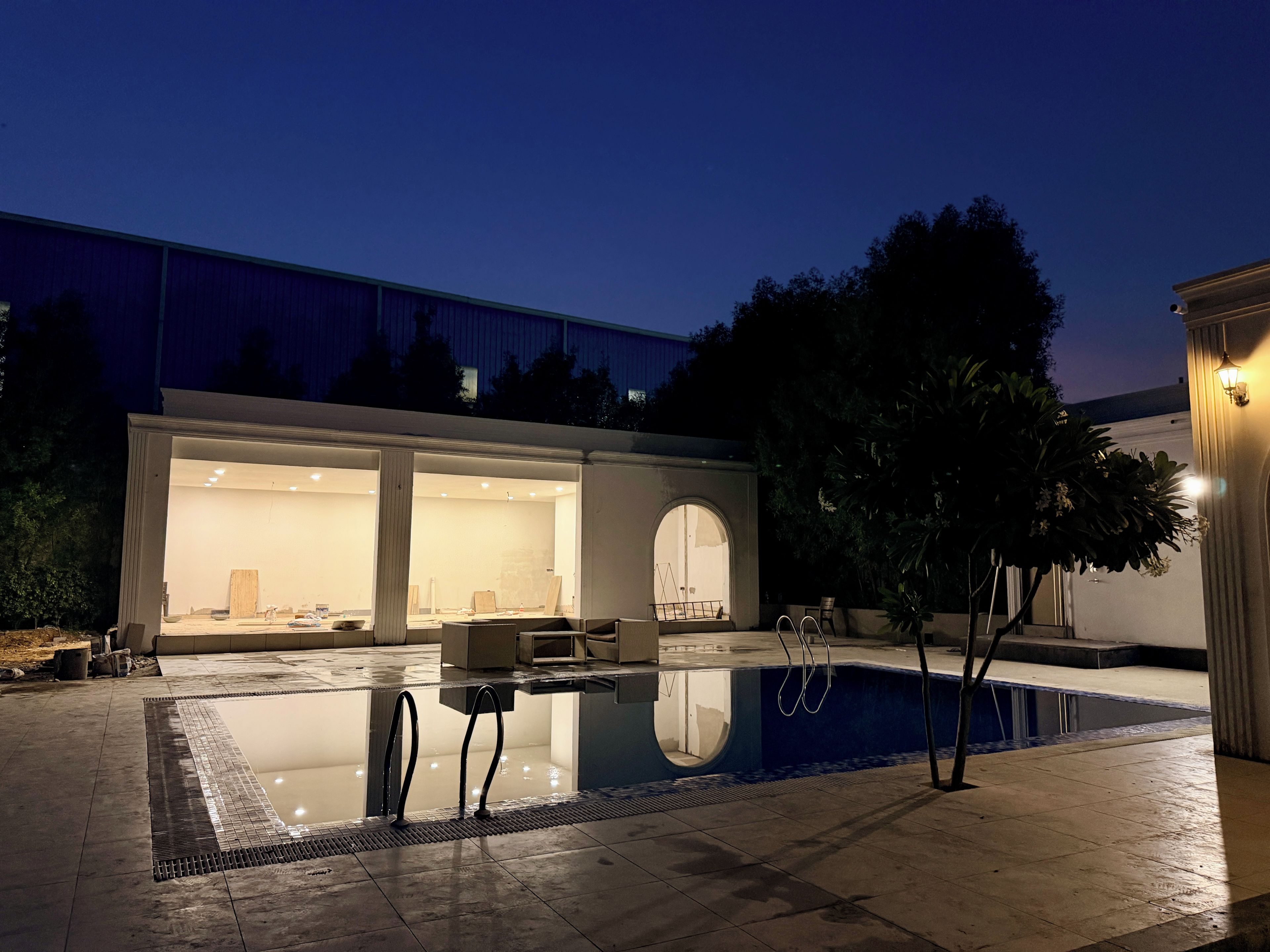 A modern house with a swimming pool, large windows, and a patio area.