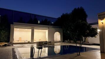 A modern house with a swimming pool, large windows, and a patio area.