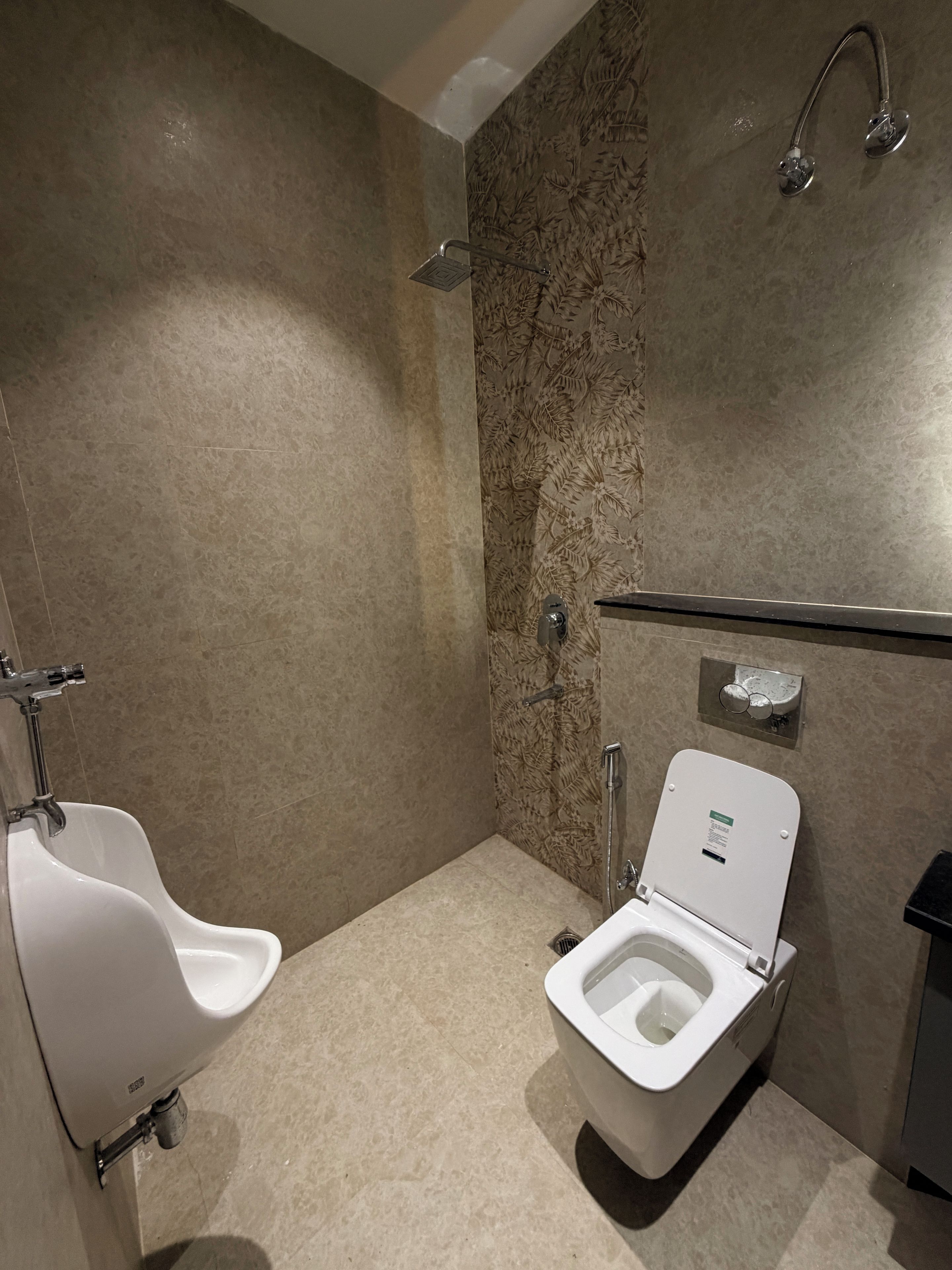 Baño de hombres con orinal, inodoro y ducha.