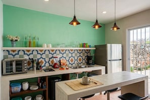 A kitchen with a toaster, sink, and refrigerator, with a tiled backsplash and hanging pendant lights. - Josefina House • Private Pool - Rooftop - Parking - Historic Center (Mérida)