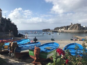 Escena costera con barcos amarrados, un acantilado rocoso y un faro.