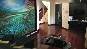 Ein Wohnzimmer mit einem großen Gemälde, einer Treppe, einem Flachbildfernseher und Holzboden.