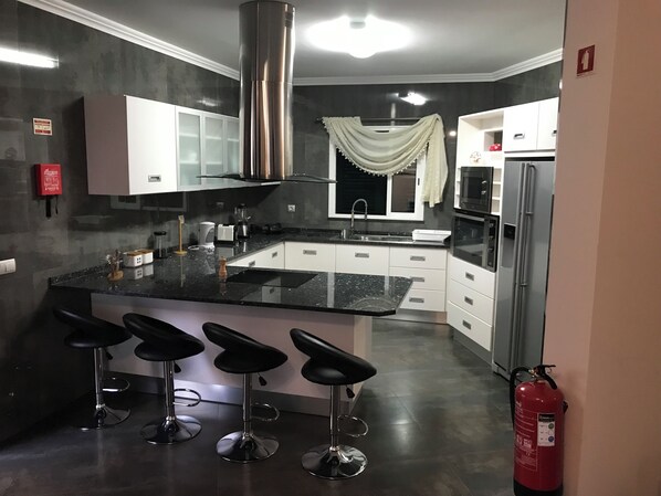 A modern kitchen with a black countertop, white cabinets, stainless steel appliances, and a fire extinguisher.