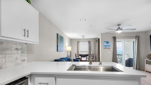 A modern kitchen with white cabinetry, a built-in dishwasher, and a large island with a sink. - Gulf Island 532 (Navarre)