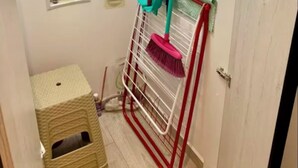 En smal hall med en hållare för kvastar, en liten pall och eluttag på väggen.