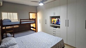 A bedroom with a bunk bed, a single bed, a TV, and a wardrobe.