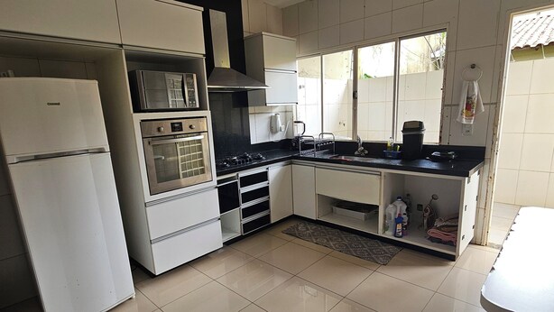 A kitchen with white cabinets, a refrigerator, a stove, and a sink.