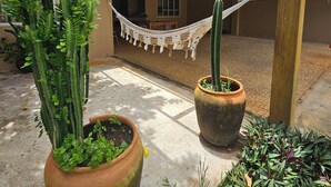 A covered outdoor area with a hammock, potted plants, and a wooden structure.