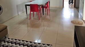 A spacious living area with a dining table, red chairs, a sofa, and a patterned rug.