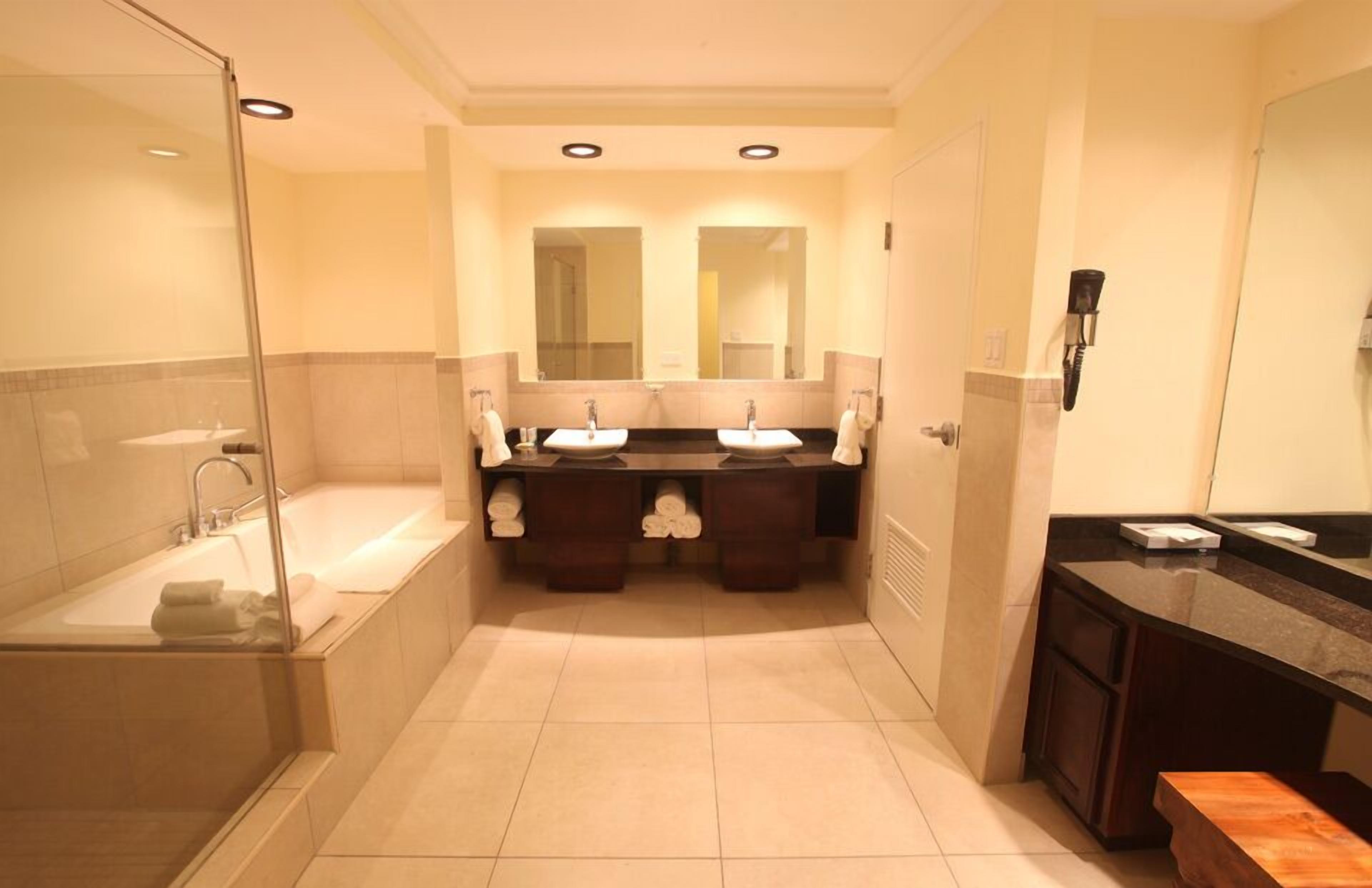 Une salle de bain dotée d’une douche à parois de verre, de deux lavabos, d’un grand miroir et d’un meuble-lavabo avec un plan de travail.