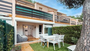 Et moderne hus med terrasse, spiseplads og overdækket udendørs siddeområde.