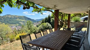 A covered outdoor dining area with a table and chairs, overlooking a scenic valley. - Châlet Pré Gaillard - proche du centre la Bresse (La Bresse)