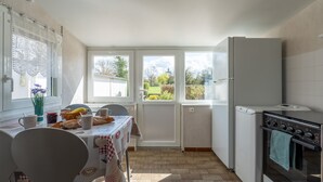 A kitchen with a dining table, chairs, a refrigerator, and an oven. - La Petite Solognote - Proche Châteaux de la Loire (Cour-Cheverny)