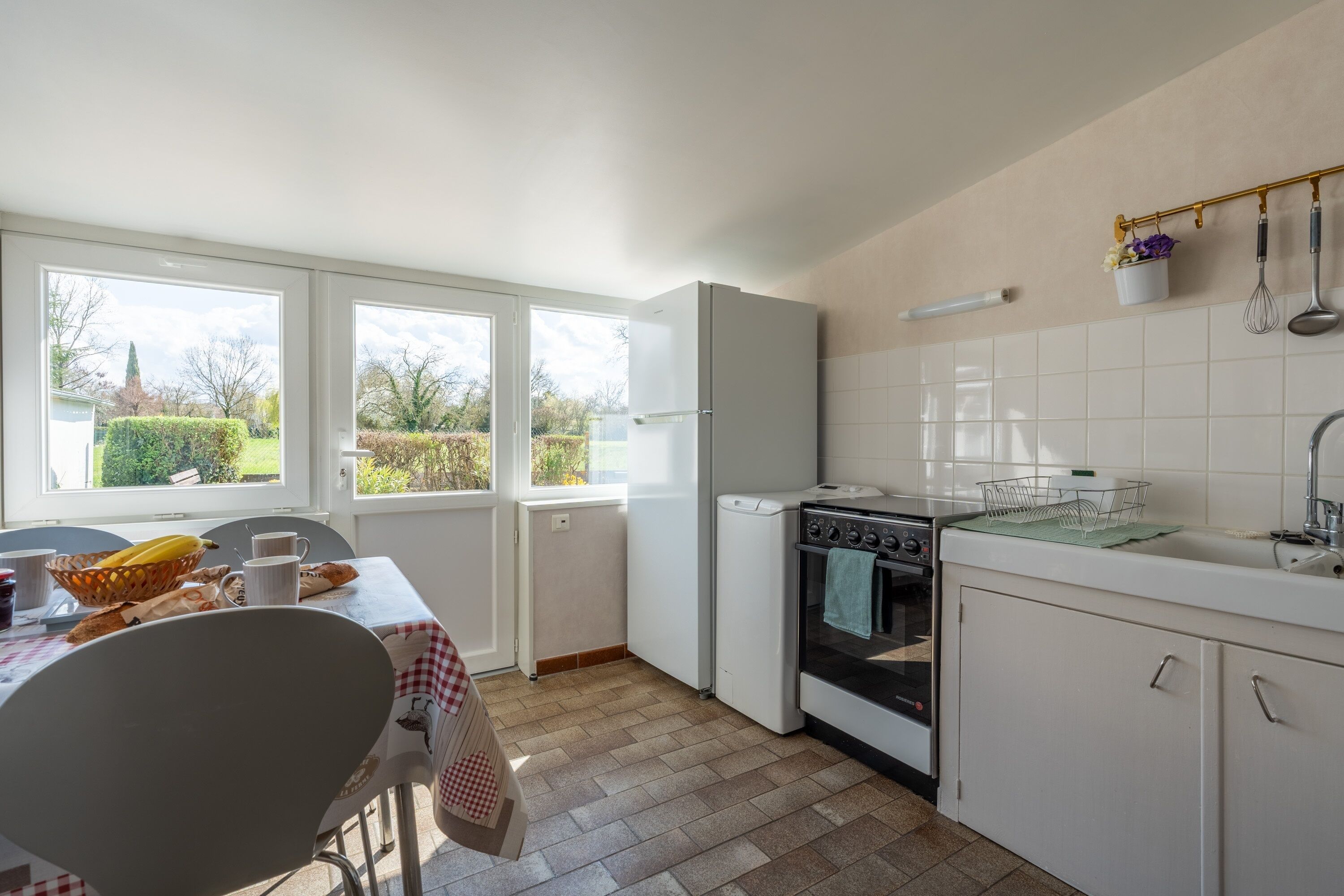 Una cocina con mesa de comedor, lavadora, horno y ventana con vistas a zonas verdes.