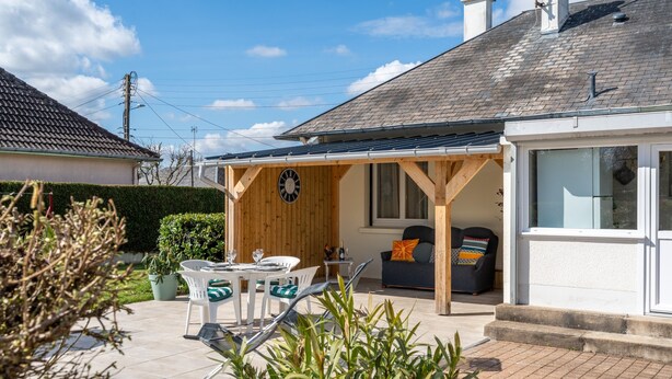 A house with a covered patio, a dining table with chairs, a sofa, and a clock on the wall. - La Petite Solognote - Proche Châteaux de la Loire (Cour-Cheverny)