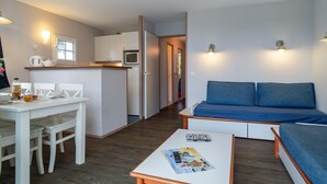Ein kompakter Wohnbereich mit Küchenzeile, Essbereich und einer Sitzecke mit Sofa.