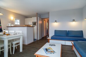 Ein kompakter Wohnbereich mit Küchenzeile, Essbereich und einer Sitzecke mit Sofa.
