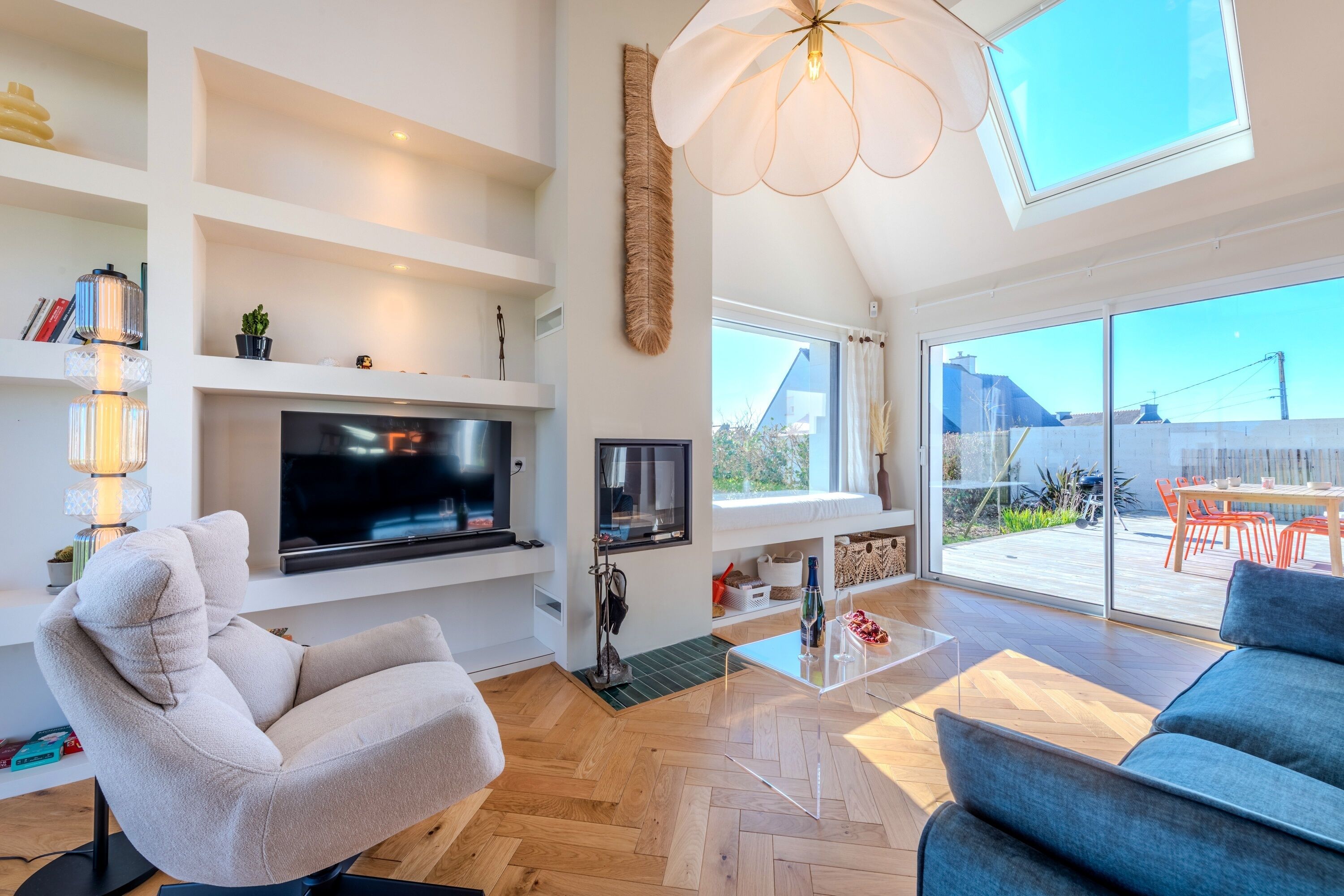 A spacious living room with a flat-screen TV, comfortable seating, a large window, and a balcony.