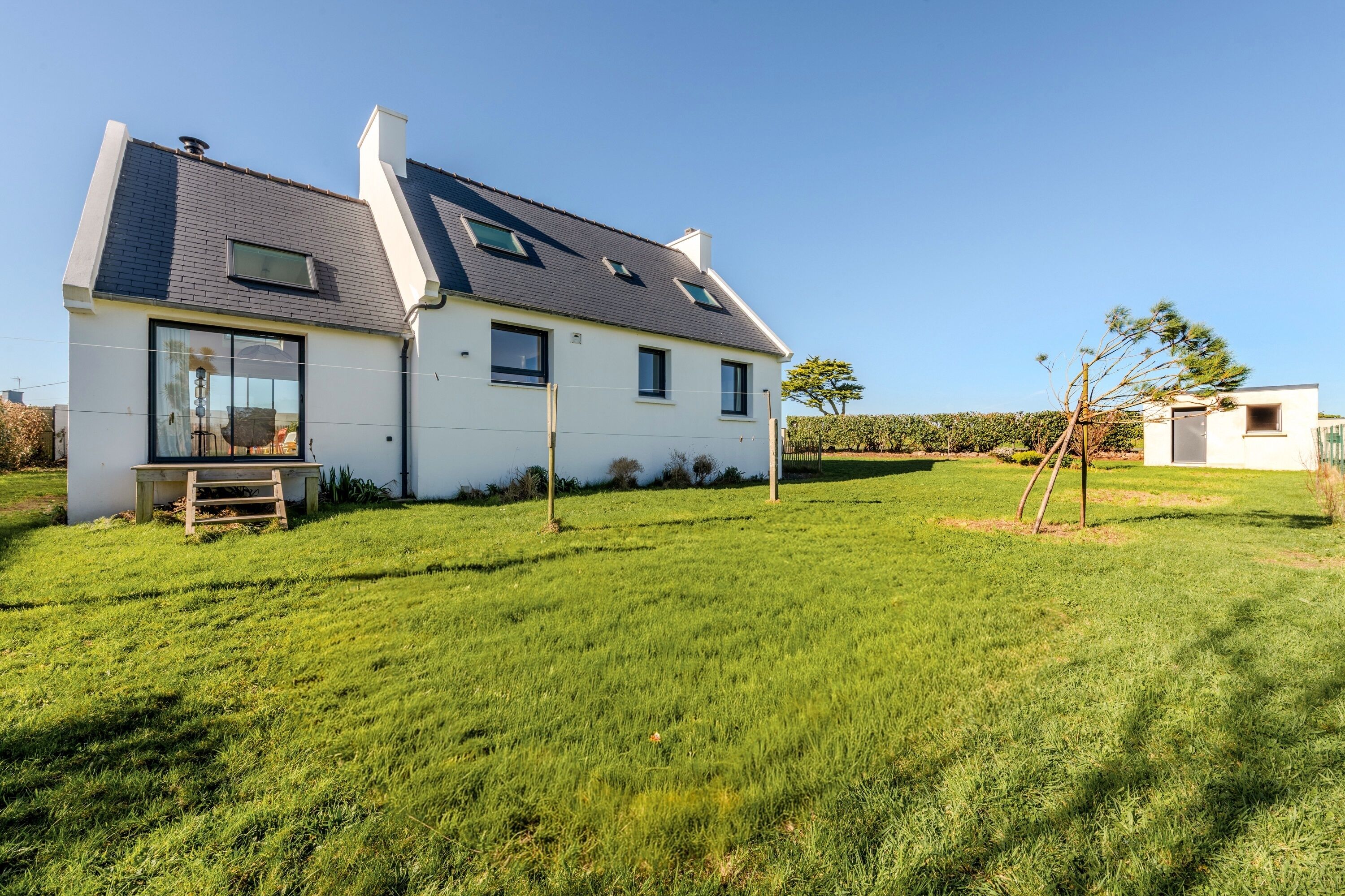 A modern house with a sloped roof, large windows, and a well-maintained lawn.