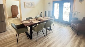 Comedor con techo de madera, ventilador de techo, mesa y sillas, y vistas al exterior a través de una ventana.