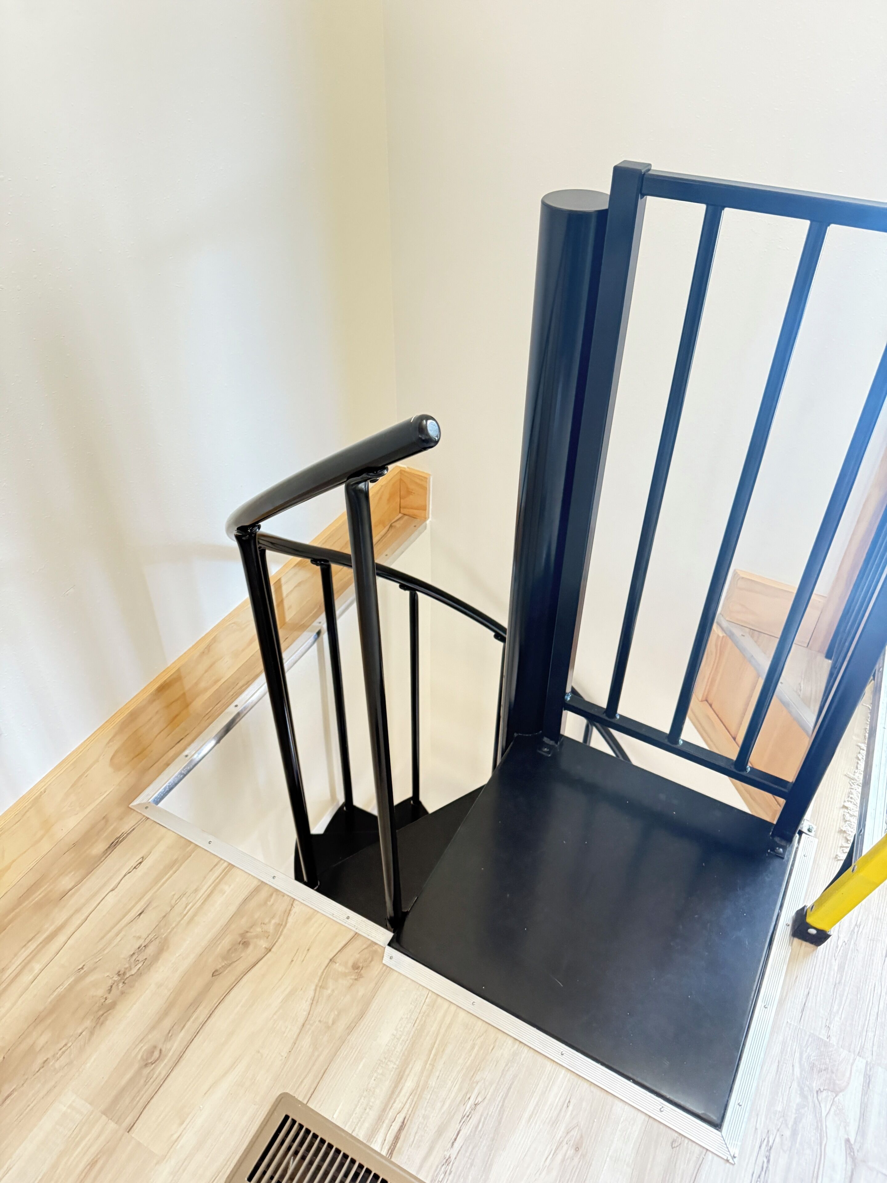 A black metal chair with a wooden floor and a white wall.
