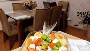 Ein Essbereich mit einem Glastisch, Stühlen und einem Laptop auf dem Tisch.