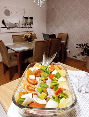 Un comedor con una mesa de vidrio, sillas y un ordenador portátil sobre la mesa.