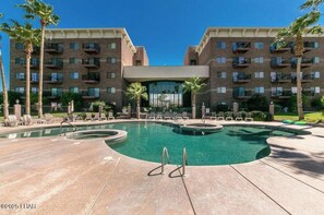 A hotel with a pool, palm trees, and a brick facade. - Lovely Lake Condo -London Bridge Views - Remodeled 2 Bed- 2 Bath beautiful! (Lake Havasu City)